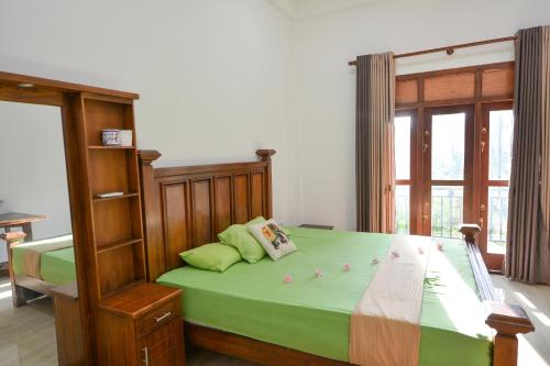 a bedroom with a bed with green sheets and a window at Sun Side Villa in Ginimellagaha West