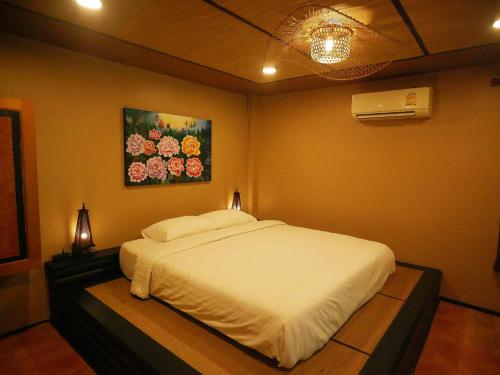 a bedroom with a white bed with a painting on the wall at Big Elk Steak House - HomeStay in Trat