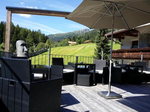 un patio con sombrilla, mesas y sillas en Schweiger en Sankt Anton am Arlberg