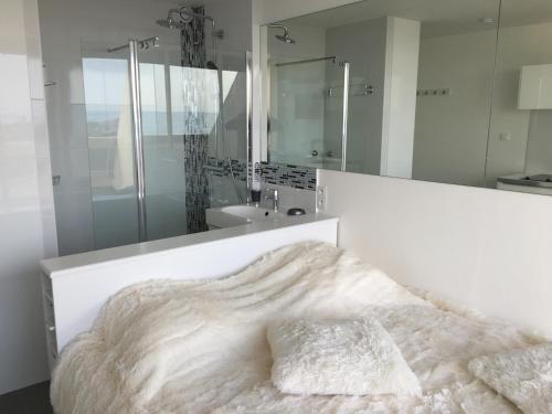 a white bedroom with a bed and a mirror at Studio face Mer - Village Naturiste - Cap d'Agde in Cap d'Agde