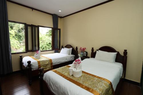 a hotel room with two beds with flowers on them at We House River View Hotel And Travel in Luang Prabang