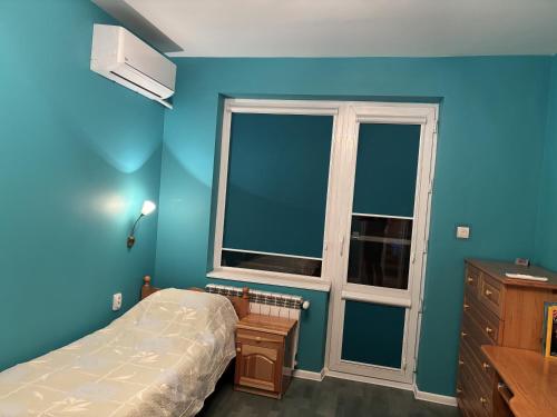 a bedroom with blue walls and a bed and a window at Galina apartment in Ruse