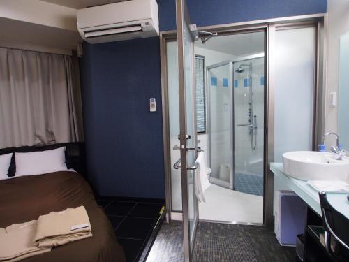a bedroom with a bed and a bathroom with a sink at Urbain Hiroshima Executive in Hiroshima