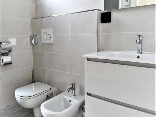 a white bathroom with a toilet and a sink at Modern villa close to the beach in Lignano Sabbiadoro