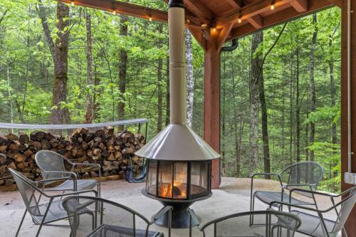 a porch with chairs and a lamp and a pile of logs at A-Frames Under the Canopy - Multi-Cabin Retreat in Rogers