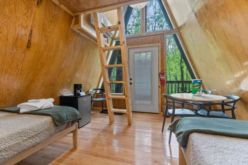a room with two beds and a ladder and a table at A-Frames Under the Canopy - Multi-Cabin Retreat in Rogers