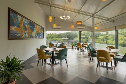 The Nest, Karjat في كارجات: غرفة طعام مع طاولات وكراسي ونوافذ