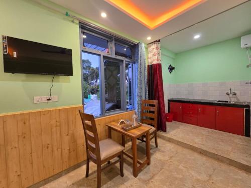 a kitchen with a table and a tv on the wall at Aangan Royal Stay in Dharmsala