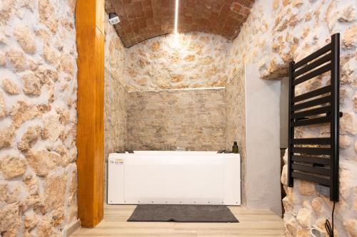 a bathroom with a white tub in a stone wall at Ca La Padrina in Torre del Español