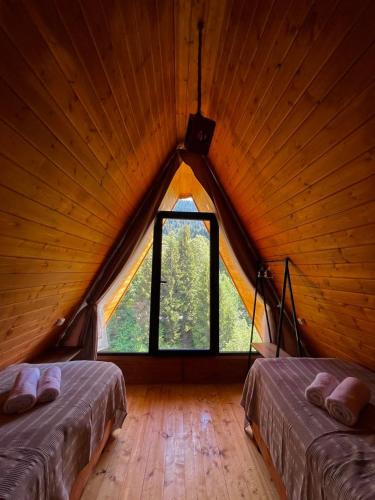 a attic room with two beds and a large window at Rock Cabins Svaneti in Mestia