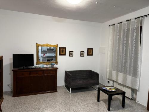 ein Wohnzimmer mit Fernseher, Sessel und Spiegel in der Unterkunft La Vecchia Chiassaia (mare/montagna) in La Pescaia