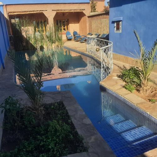 ein Swimmingpool in einem Garten mit einem blauen Haus in der Unterkunft Kasbah Petit Nomade in Tinghir