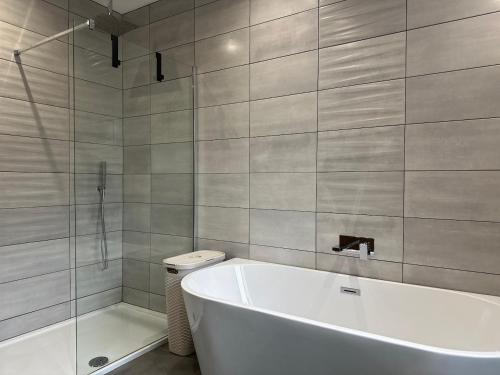 a white bath tub in a bathroom with a shower at Modern Retreat with Hot Tub and Cinema in Cuckney