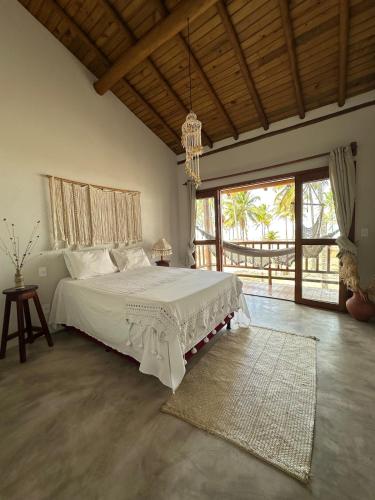 a bedroom with a large bed and a large window at Casa de praia exclusiva, pé na areia em Mogiquiçaba, Bahia in Belmonte