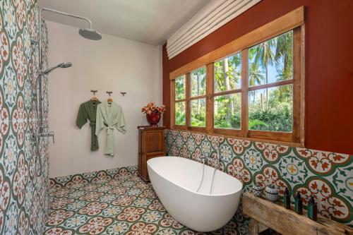 ein Bad mit einer Badewanne und einem Fenster in der Unterkunft Moorea Boutique Resort Samui in Ban Tai