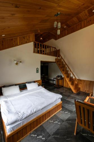a bedroom with a large bed and a staircase at Eden Stay & Cafe in Jibhi