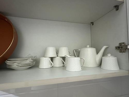 un estante con jarrones y platos blancos encima en Veridian Villa, en Kānpur