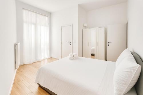 a white bedroom with a white bed and a window at Cozy Brabanconne apartment in Brussels