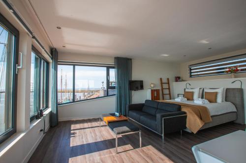 a bedroom with a bed and a couch and windows at Slapen in een Trechter in Harlingen