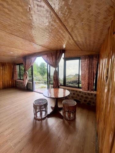 a room with a table and two chairs and windows at Annapurna Nature Retreat, Namchi South Sikkim in Singtām