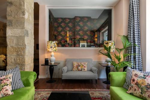 a living room with two green couches and a mirror at Hotel Carmen Boutique in Baeza