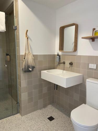 a bathroom with a sink and a toilet and a mirror at Archy's on the Lake in Burrill Lake
