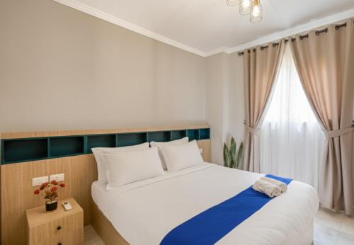 a bedroom with a large white bed and a window at Travelholic Residence Near Mivida in Cairo