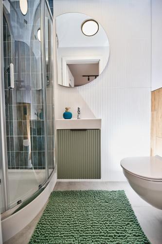 a bathroom with a shower and a green rug at Zefir Apartment in Rzeszów