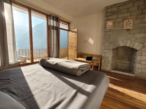 a bedroom with a large stone fireplace and a bed at Samora Retreats, Manali in Vashisht