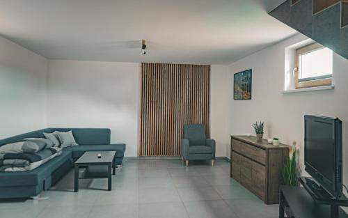 a living room with a blue couch and a tv at Dziki Raj - domki z widokiem na Tatry oraz Babią Górę in Jabłonka