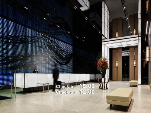 a man is standing in a lobby with a wall at Millennium Mitsui Garden Hotel Tokyo - Ginza in Tokyo