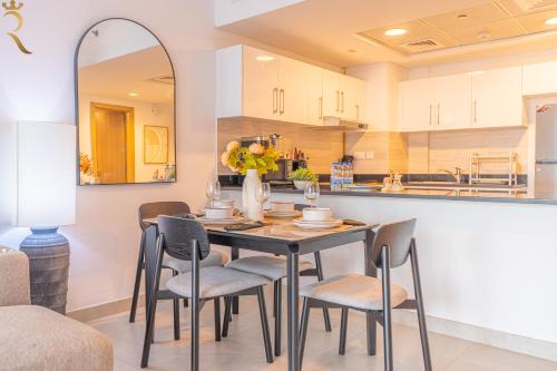 a dining room with a table and chairs and a kitchen at Modern 1BR Oasis - Sleek Chic Retreat in Abu Dhabi