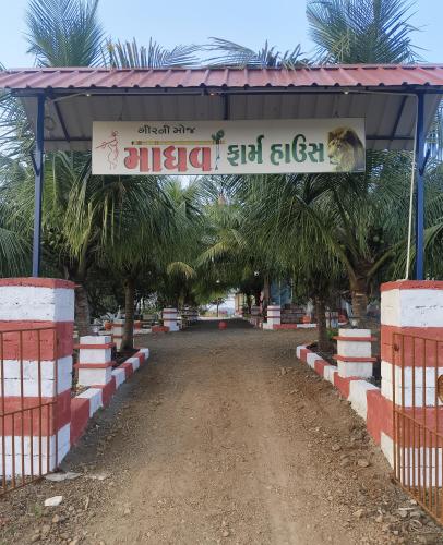 a gate to a road with a sign on it at Madhav Farmhouse in Sasan Gir
