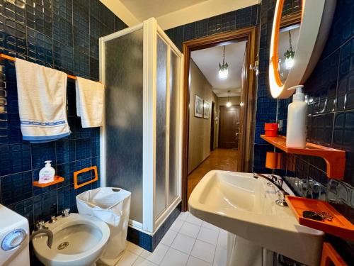 a blue tiled bathroom with a sink and a toilet at Ampio appartamento per 8 a due passi dal centro in Bardonecchia