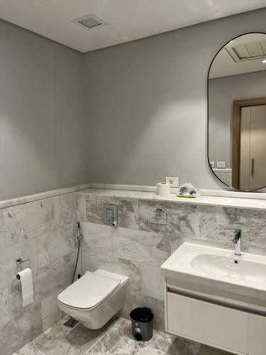 a bathroom with a toilet and a sink and a mirror at Aeon Towers 2BR in Sheikh Zayed