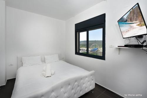 a white bed in a room with a window at סוויטת אפנדי in Ya‘ara