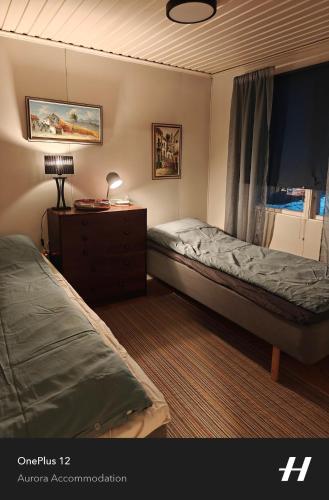 a bedroom with two beds and a dresser and a window at Aurora Lakeside Cabin Altajärvi in Kiruna