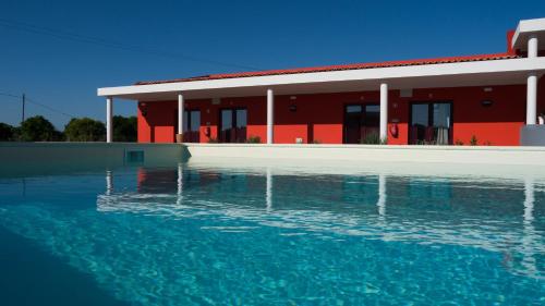 um edifício vermelho com uma piscina de água em frente em Casa d´Edite em Chamusca