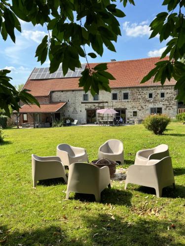a group of chairs sitting in the grass in front of a building at Le gîte d’Hayen in Sprimont