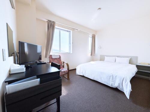 a bedroom with a bed and a desk with a television at Uwajima Oriental Hotel in Uwajima