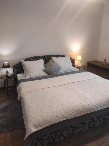 a bedroom with a large bed with white sheets and pillows at Nina apartman in Komárno