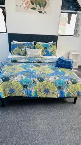 a bed with a colorful comforter on top of it at Mount Breeze in Mount Maunganui