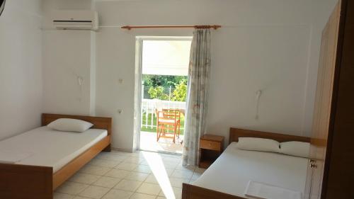 a bedroom with two beds and a window with a patio at Studios Kaintas in Agia Paraskevi