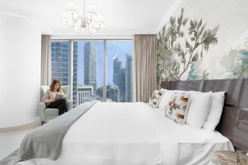 a woman sitting in a chair in a bedroom with a large bed at Boulevard Point I Burj Khalifa Fireworks View in Dubai