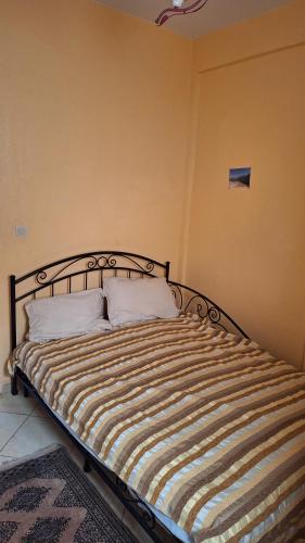a bedroom with a bed with a striped comforter at Jalila House in Aourir