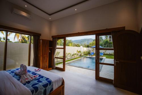 a child sitting on a bed in a bedroom with a pool at Bukti Garden Villas in Bukti