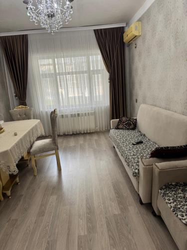 een woonkamer met een bank, een tafel en een kroonluchter bij Gala Guest House in Lankaran