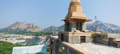 a tower on top of a building with mountains in the background at Jawai Dam Stay and Leopard Safari 
