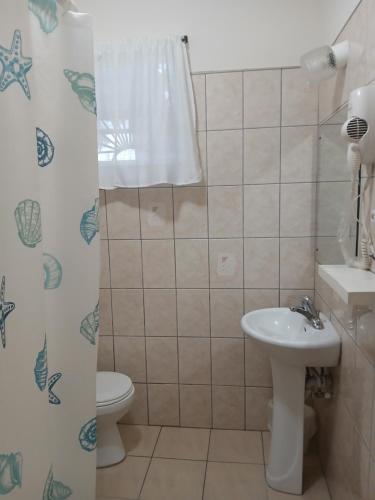 a bathroom with a sink and a toilet and a shower curtain at One Bedroom Apartment 1 minute walk to West Coast Beach! in Saint James