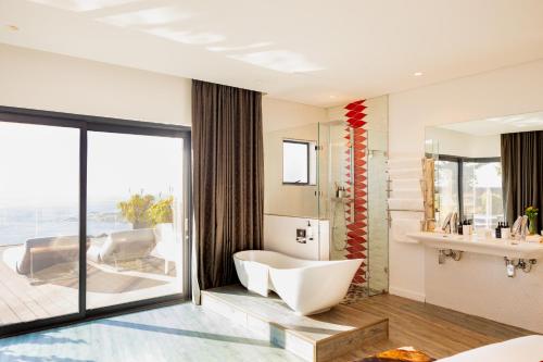 a bathroom with a tub and a sink at Sea Star Rocks Boutique Hotel in Cape Town